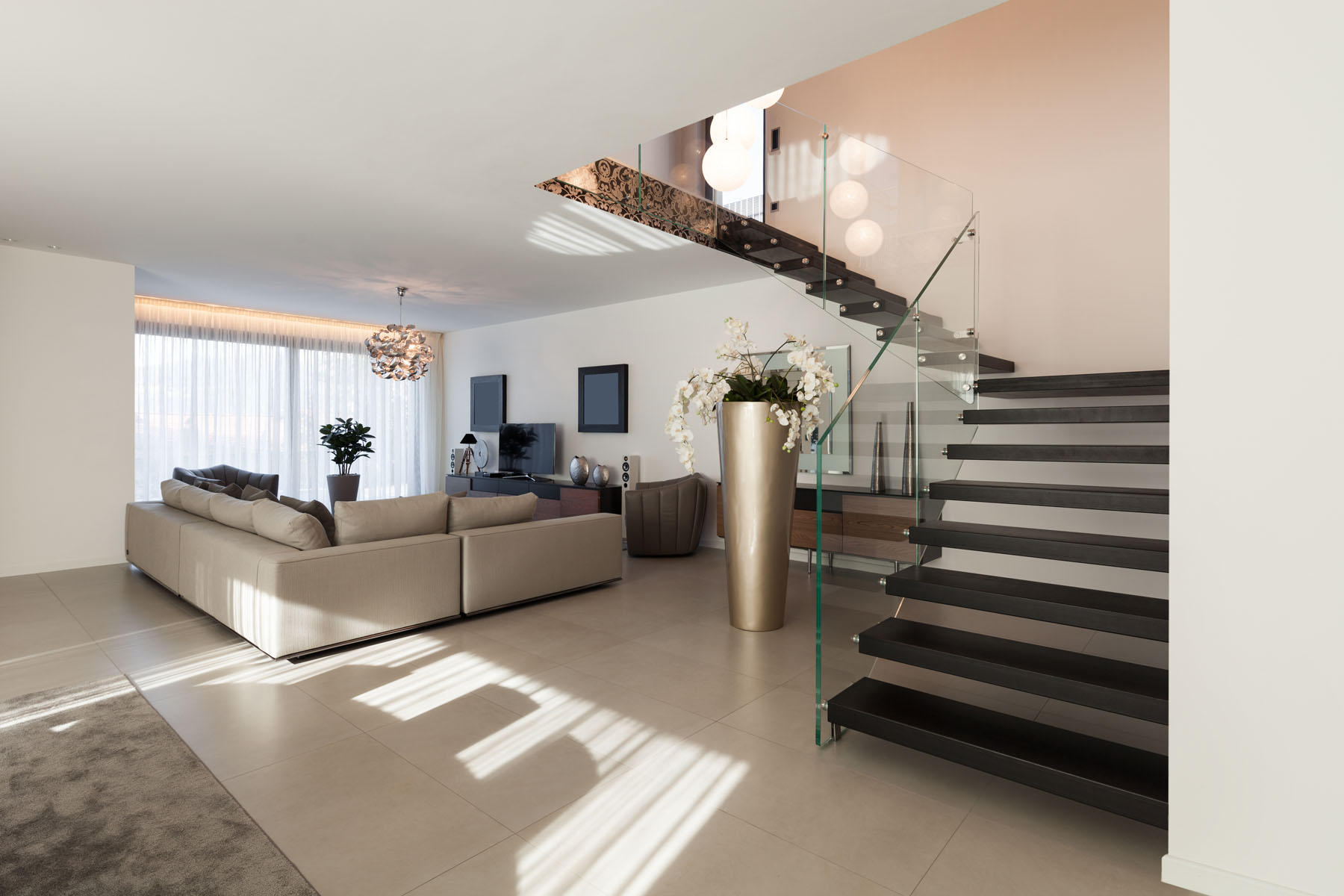 Open-plan living room with a floating dark timber staircase and glass balustrade