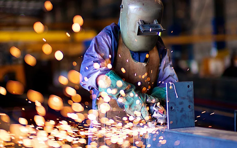 Fabricator grinding steel staircase components in the workshop