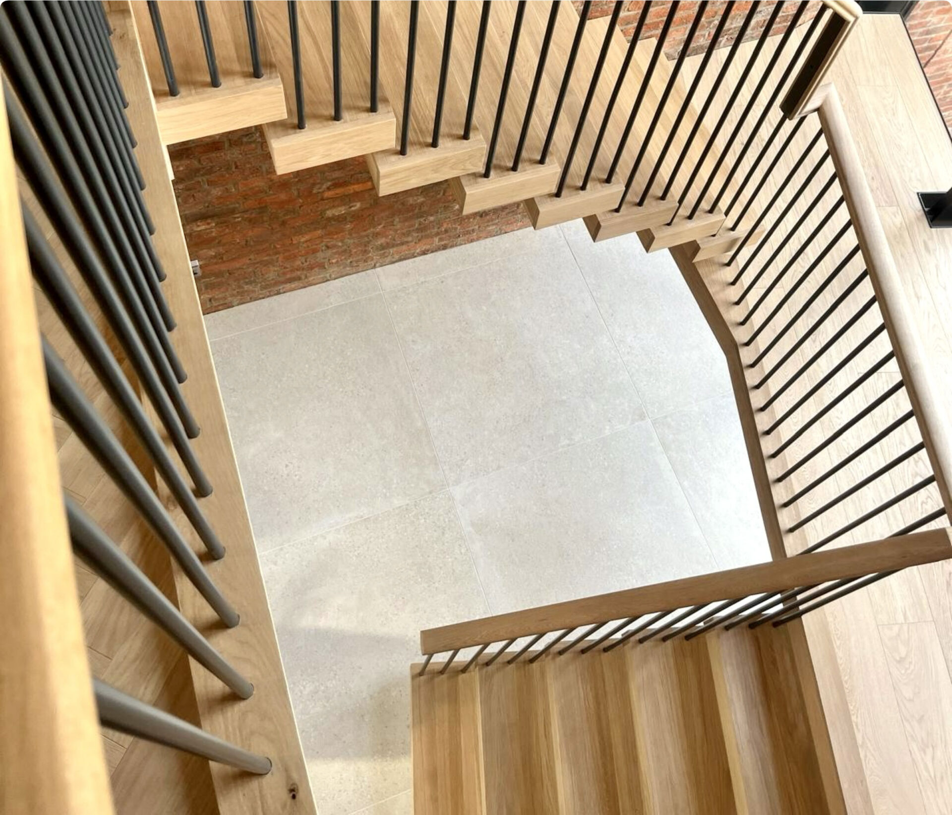 Looking down a stairwell with oak treads, black steel spindles and an oak handrail